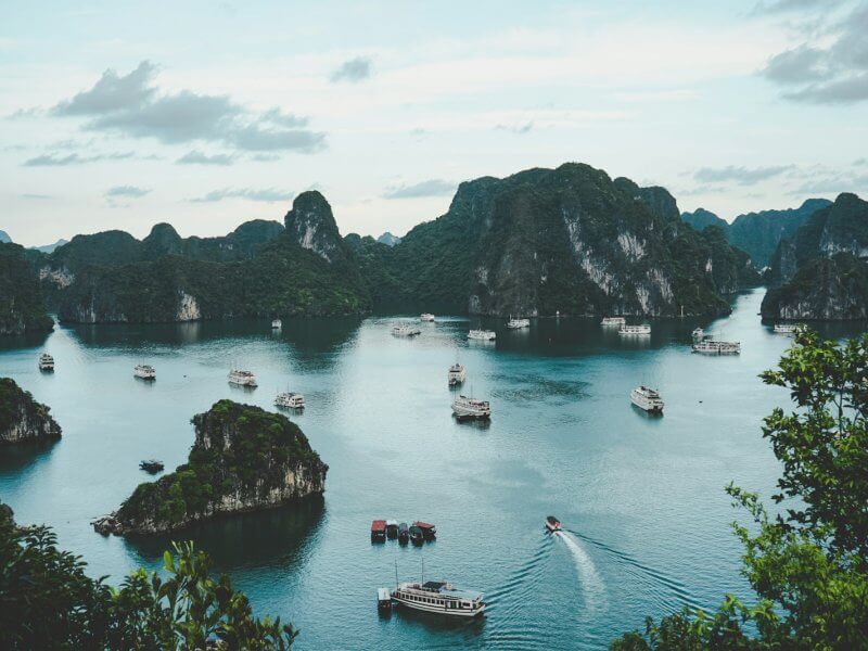 high-angle photography of boats on water near hill during daytime